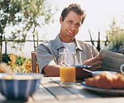 Person sitting at table outside with orange juice containing vitamin c