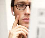 Man reading newspaper, listening to earphones, hand to face, close-up