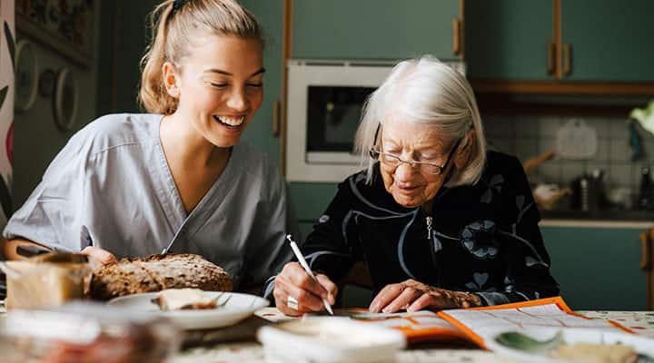 Senior woman doing a crossword puzzle with her nurse