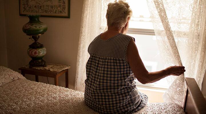 Lonely elderly woman looking out the window