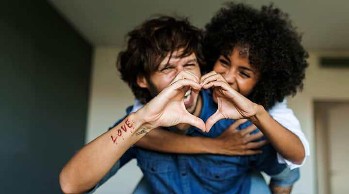 A man and woman forming a heart with their hands