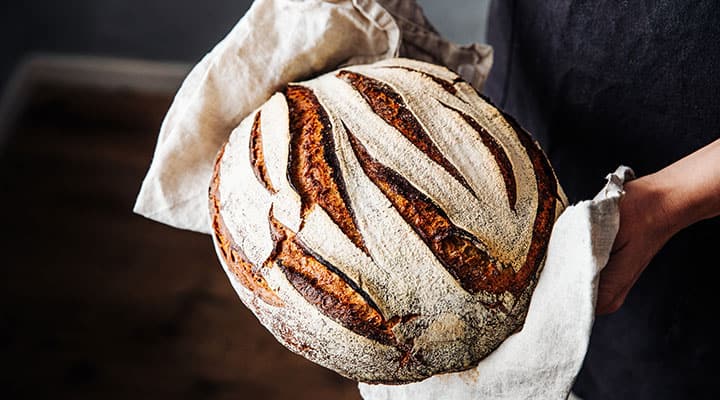 Woman holding a freshly baked loaf of rye bread