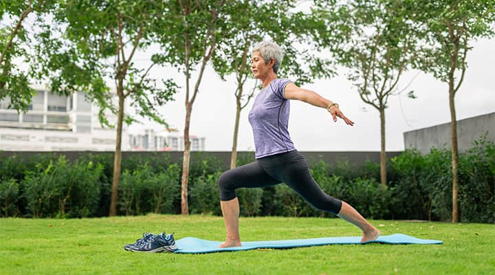 Senior woman practicing yoga outdoors on a mat