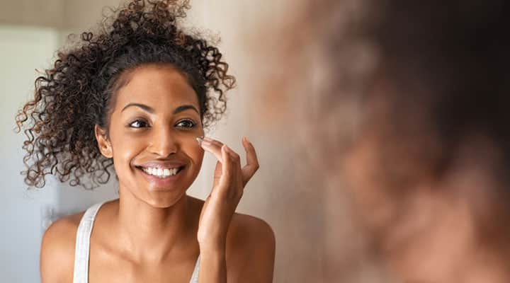 Woman applying a retinyl palmitate in the mirror