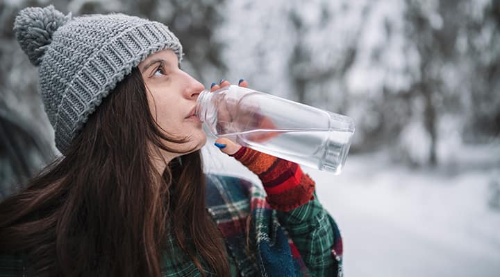 Woman drinking water outside to maintain hydration