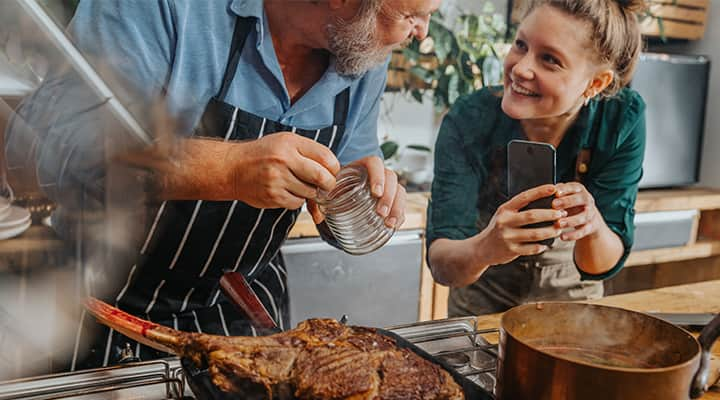 Husband and wife seasoning and cooking rib-eye steak