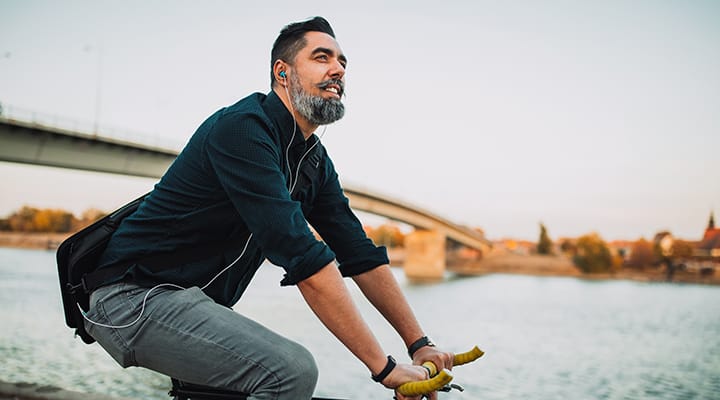 Bearded man bikes by the river