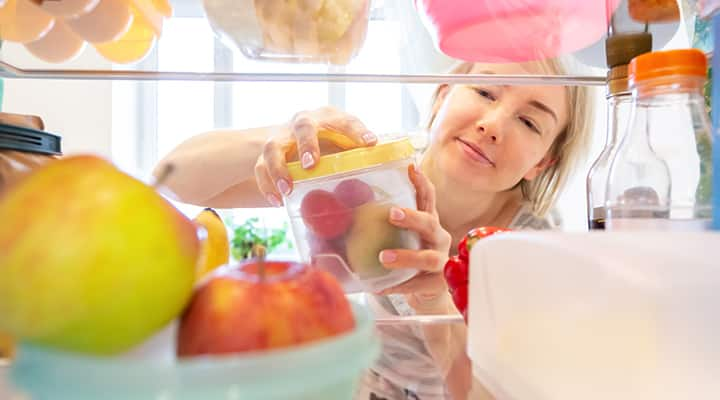 Woman opening jar of fruit for healthy grazing snack