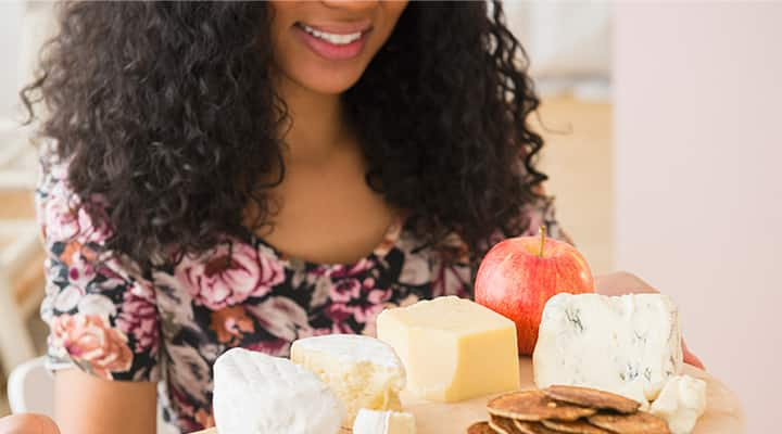 Woman holding cheese board with apple for healthy grazing foods