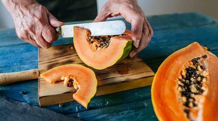 Man cutting papaya which contains digestive enzymes