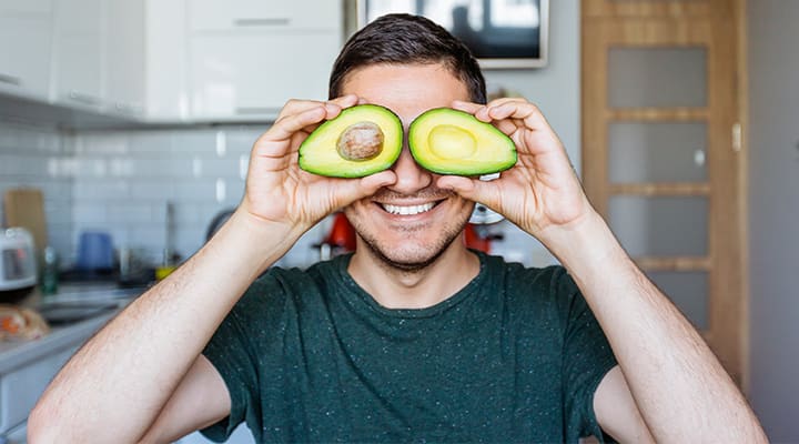 Man holding up avocado to avoid skin and seeds of fruits and vegetables