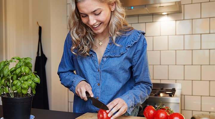 Woman chopping tomatoes for health benefits in consuming high lectin content