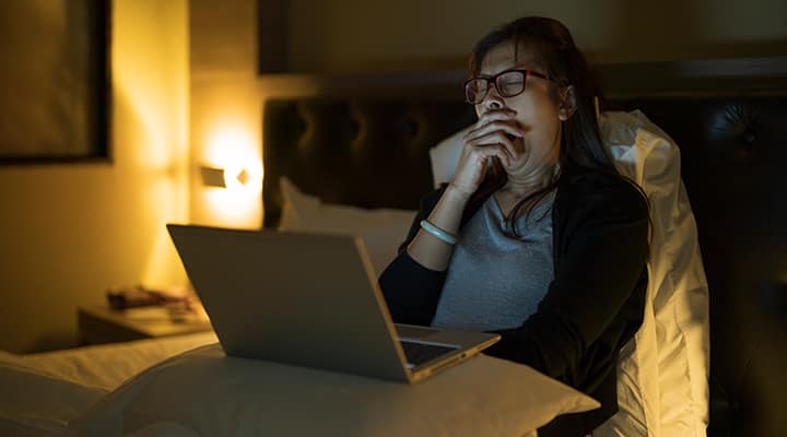 Tired woman working late on a laptop in a dark room