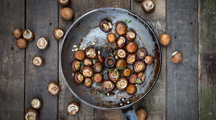 Sautéeing mushrooms with butter and garlic for added flavor on a pan