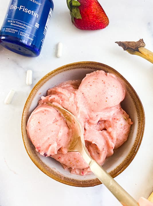 Woman taking spoonful of strawberry nice cream made from frozen fruit