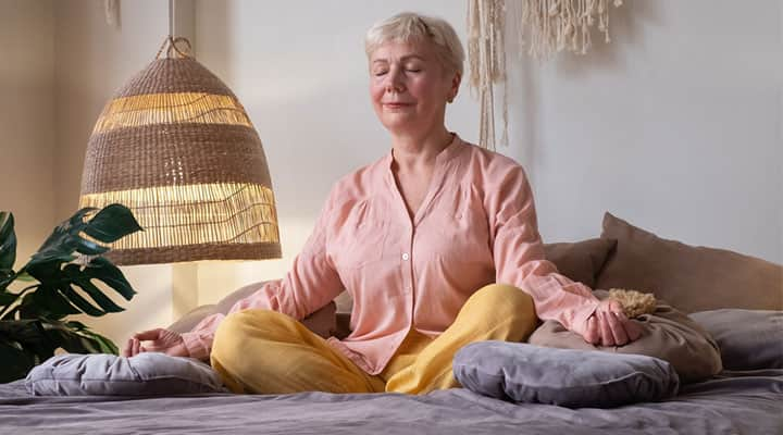 Woman doing mediation and breathing exercises in bed