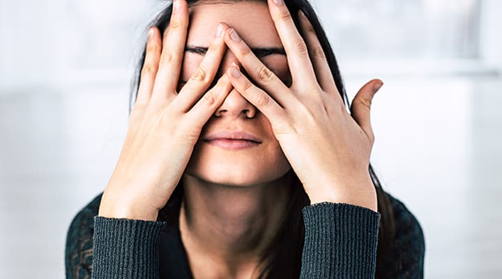 Woman with hands on face deals with mental stress