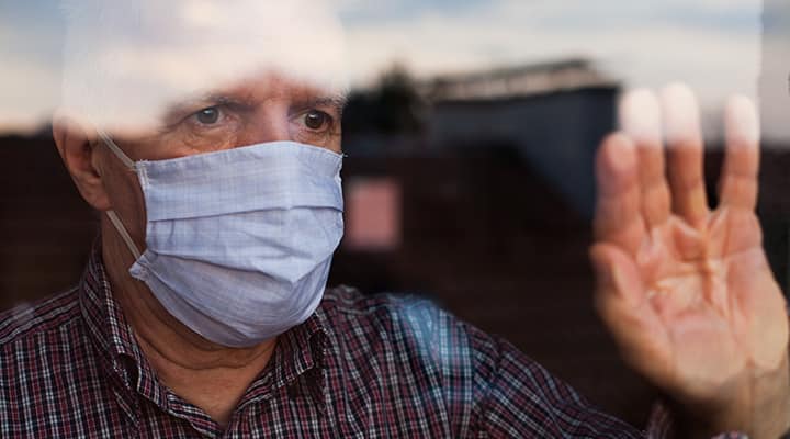 Older man in quarantine looks out window