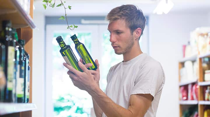 Man comparing two bottles of olive oil in a store