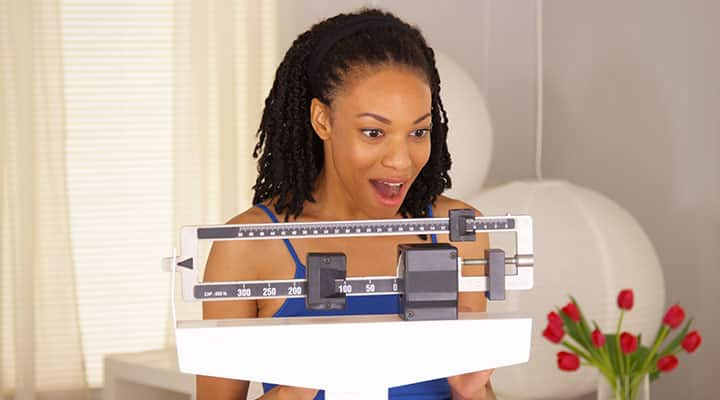 Woman on scale excited about her weight loss