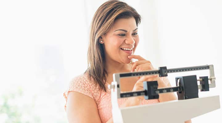 Woman weighing herself and smiling