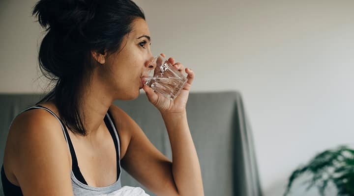 Woman drinking water to help ease a hangover