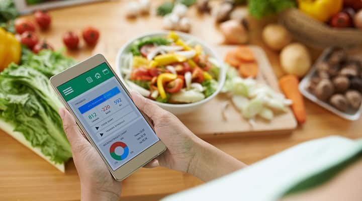 Woman holding a smartphone with a calorie counting app open