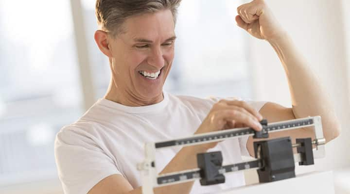 Older man standng on a scale happy about his weight