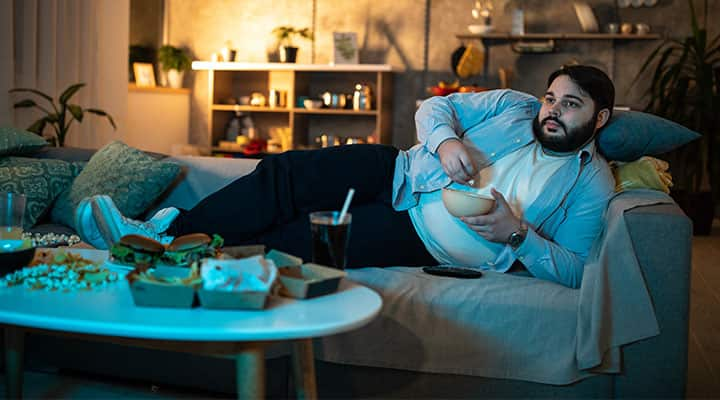 Man who has trouble managing weight laying on couch