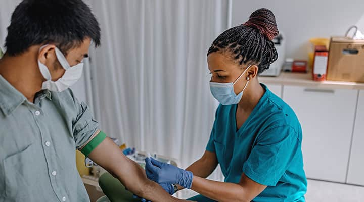 Woman taking a blood sample from a male patient