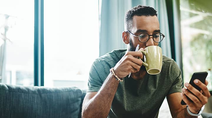 Man drinking tea and looking at his phone