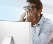 man in front of computer, rubbing strained eyes