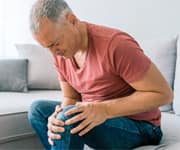 man holding painful, arthritic knee