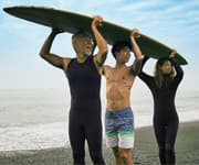 father, son and daughter holding surfboard above their heads