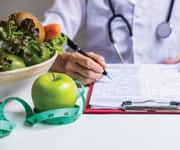 Doctor reviewing a chart in front of a salad and an apple