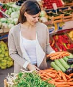 Woman grocery shopping holding carrots