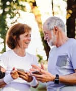 Man and woman walking in a park holding smart phones
