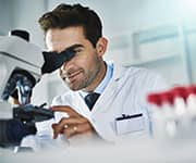 Doctor looking at blood slides through microscope