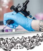 Tattoo artist dipping equipment in ink