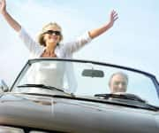 Older woman standing in car feeling youthful