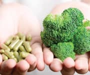 Woman holding supplements and fresh broccoli