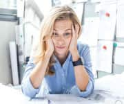 Woman stressed at office desk and at risk of work-stress burnout