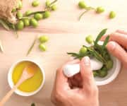 Woman pressing olives for olive oil that has whole body health benefits