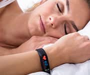 Woman with health wristband used for monitoring quality restorative sleep