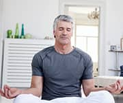 Man meditating in bedroom as part of falling asleep faster and for longer