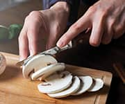 Woman cutting button mushrooms to being added for increased consumption