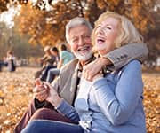 Senior man and woman laughing in park enjoying the benefits of walnuts