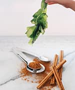 Woman holding green seaweed and cinnamon stick that contain compounds that reduce glucose levels