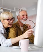 Senior couple laughing while reading on the computer