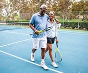 Husband and wife walking off tennis court for exercise to mitigate bone-related illnesses